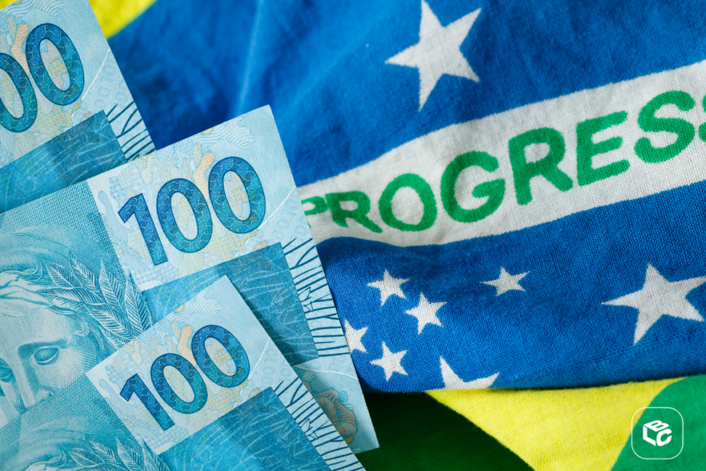 Notas de 100 reais sobre a bandeira do Brasil com a palavra PROGRESSO
