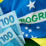 Notas de 100 reais sobre a bandeira do Brasil com a palavra PROGRESSO